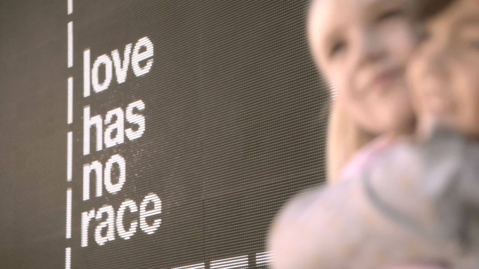 Blurred image of two children hugging next to digital sign that reads 