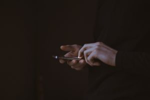 Hands of a man using a smart phone to send a text