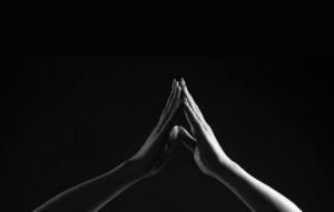 Black and white photo of two hands with fingers touching each other in a triangle shape