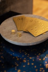 Gold playing cards and two gold dice lying on a small, round stone platter