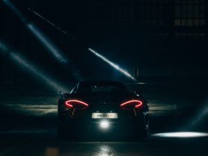 McLaren 600 LT automobile in dark warehouse with its lights on